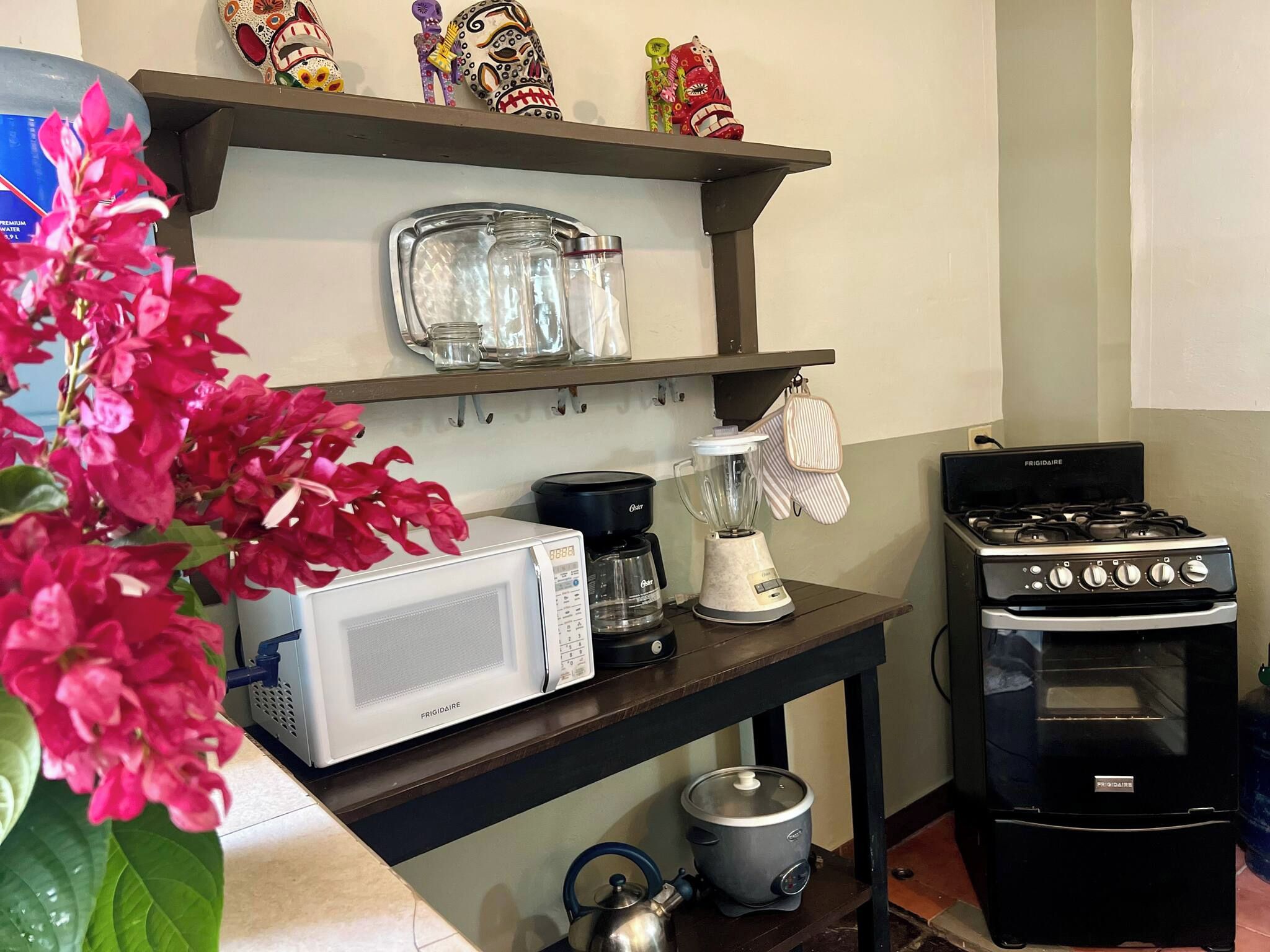 Una cocina equipada con microondas, cafetera, hervidor y estufa.