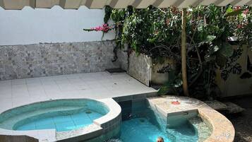 A swimming pool with a tiled deck and a hot tub area.