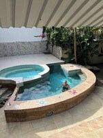 Una piscina con solárium azulejado y zona de hidromasaje.