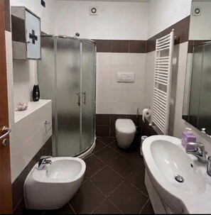A modern bathroom with a glass shower enclosure, a bidet, a toilet, and a sink. - Strategically located near downtown Milan, Bocconi, San Siro, Assago, and Humanitas. (Rozzano)