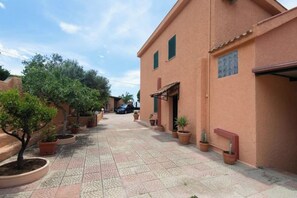 A courtyard with potted plants and a building with a tiled floor. - Villa Adelaide | Private Pool, 5 Bedrooms, and the Ocean Just 100 Meters Away (Reggio Calabria)