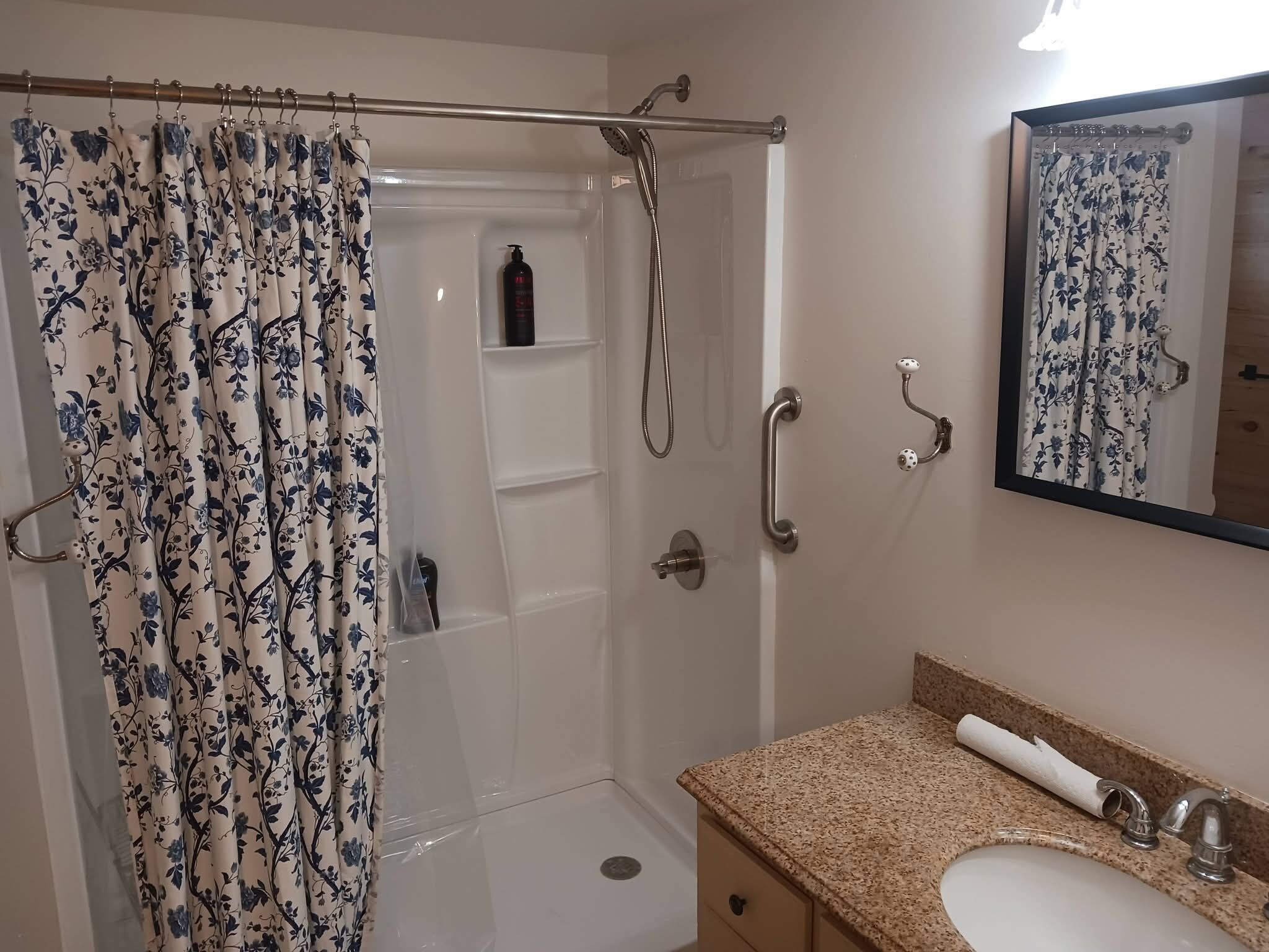Et badeværelse med bruser, toilet, håndvask og spejl.