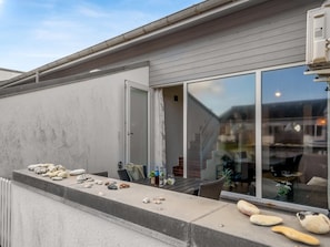 A patio with a table set with stones, a chair, and a glass of water. - "Alena" - 50m from the sea by Interhome (Brovst)