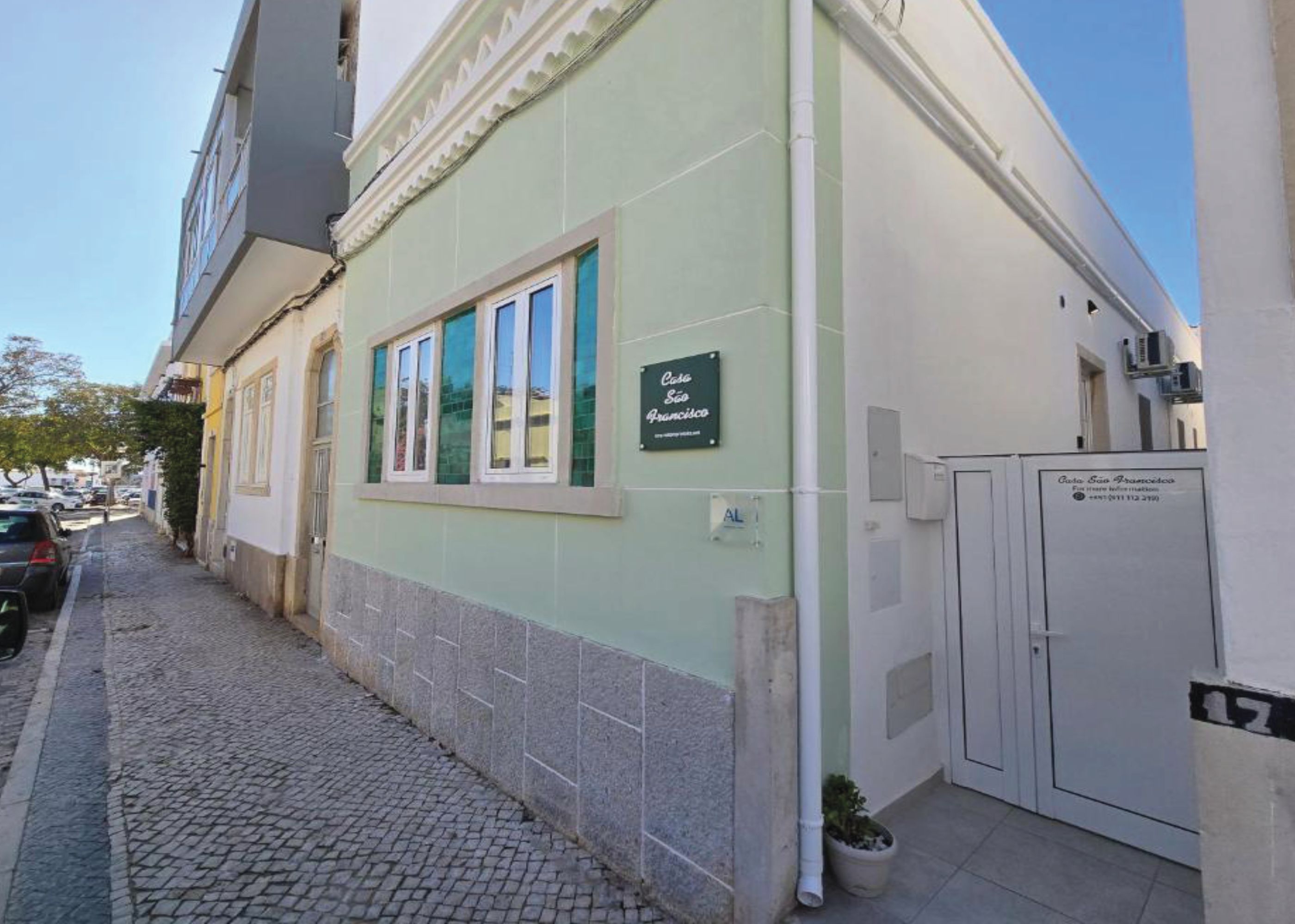 A building with a green facade, a sign reading 'Casa São Francisco,' and a tiled ground.