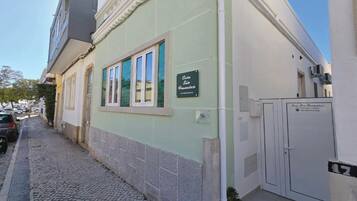 A building with a green facade, a sign reading 'Casa São Francisco,' and a tiled ground.