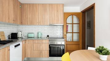 A kitchen with wooden cabinets, a white tiled backsplash, a stove, a toaster, and a coffee maker.