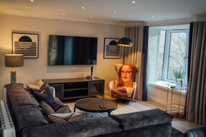 Ein modernes Wohnzimmer mit einer Couch, einem Couchtisch, einem Fernseher und einem dekorativen Sessel.