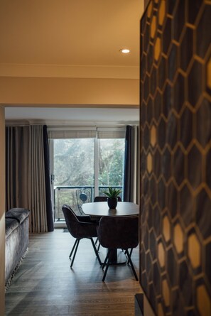 A modern dining area with a round table and chairs, a potted plant, and a view through a large window. - Eagleside Apartments - 18 - sleeps 6 guests  in 3 bedrooms (Auchterarder)