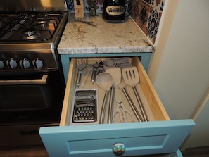 Uma gaveta de cozinha com diversos utensílios e uma cafeteira.
