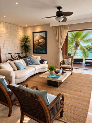 A modern living room with a white sofa, wicker chairs, a coffee table, and a ceiling fan. - Luxury Peninsula Condo with Canal and Ocean Views / Newly Renovated / 3 Bedrooms (Puerto Aventuras)