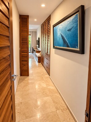 A hallway with a wooden door, a framed picture of a whale, and a tiled floor. - Luxury Peninsula Condo with Canal and Ocean Views / Newly Renovated / 3 Bedrooms (Puerto Aventuras)