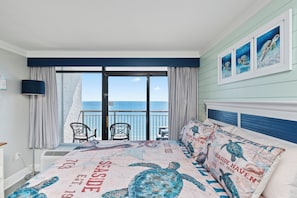 Ein Schlafzimmer mit Meerblick, ein Bett mit Meeresschildkrötenmuster und ein Balkon mit Stühlen.
