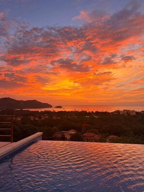 A pool with a view of a sunset over a coastal landscape. - Casa de Shanti: Private Ocean-View 4BR Retreat with Infinity Pool & Hot Tub (Coco)