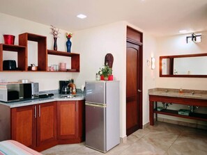 A compact kitchen with wooden cabinets, a stainless steel refrigerator, a microwave, and a coffee maker. - Casa de Shanti: Private Ocean-View 4BR Retreat with Infinity Pool & Hot Tub (Coco)