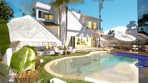 Ein modernes Haus mit Swimmingpool, Sitzgelegenheiten im Freien und einem großen Sonnenschirm.