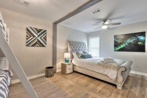 A bedroom with a bed, a nightstand, a ceiling fan, and artwork on the walls. - Huge 7BR Beach Duplex – Walk to Sand & Surf (Daytona Beach)