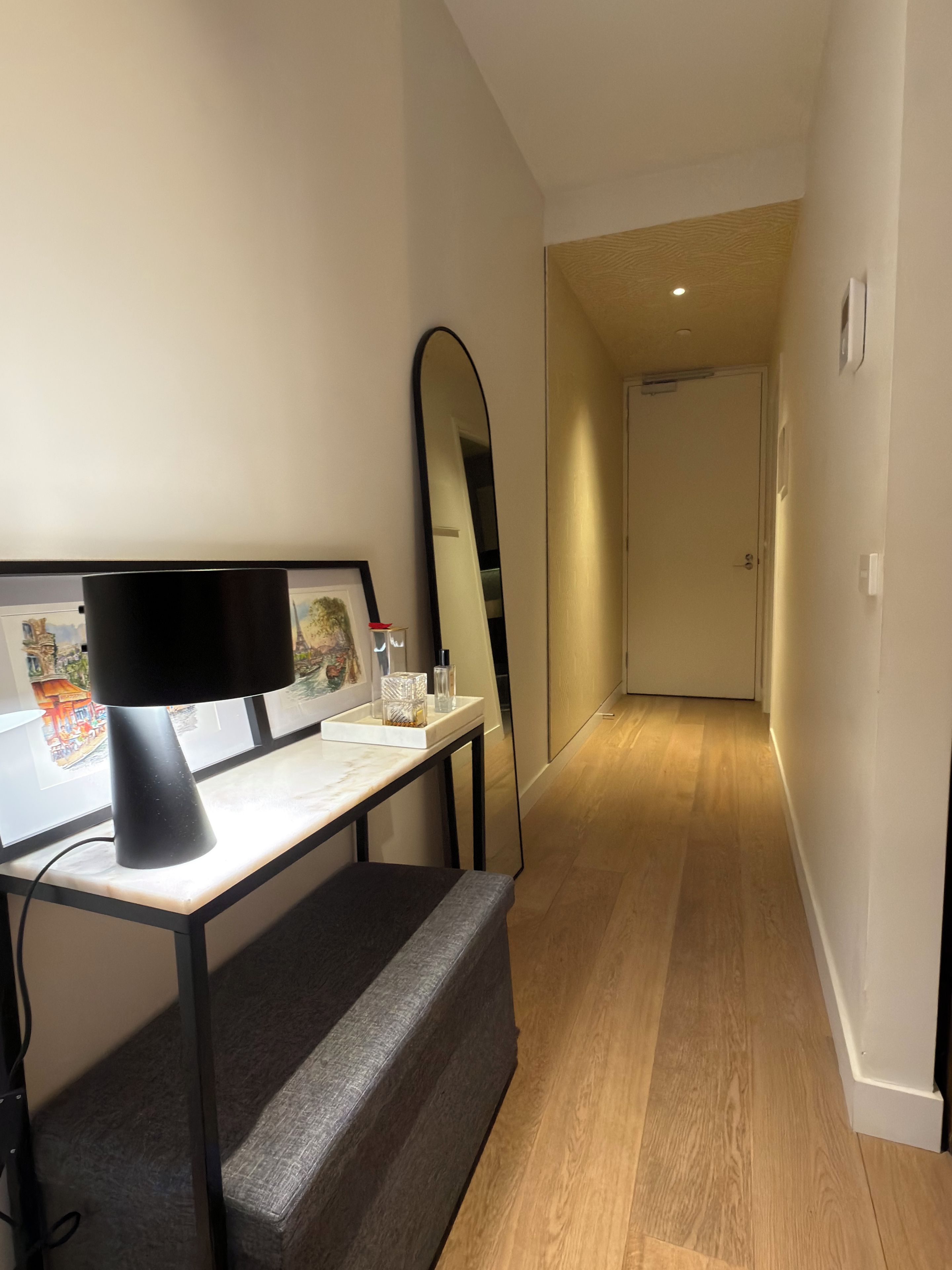 A modern room with a desk, a large mirror, and a bench.