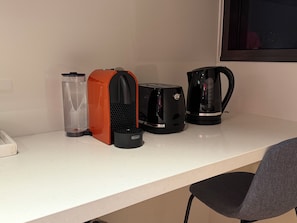 Eine Küchenzeile mit Kaffeemaschine, Toaster, Wasserkocher und einer Wasserflasche auf einer Arbeitsplatte.