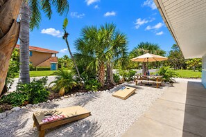 Tropical patio with cornhole, picnic table, and sunny outdoor space - Beachy Keen Bungalow- 2Br King/Bunk (Holmes Beach)