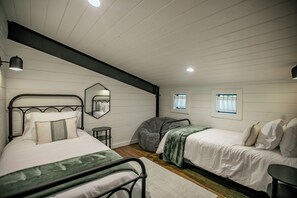 A bedroom with two beds, a mirror, a window, and a small table. - "Rest & Redeem" New Luxury Cabin in Broken Bow (Broken Bow)