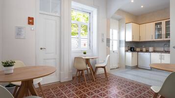 A clean, modern kitchen with white cabinets, a dining area with a table and chairs, and patterned floor tiles.