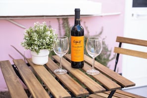 A bottle of wine with a label, two empty wine glasses, and a potted plant on a wooden table. - Casa Dona Irene Sunny Terrace | Room 1 | Early or Late Check-in (Faro)