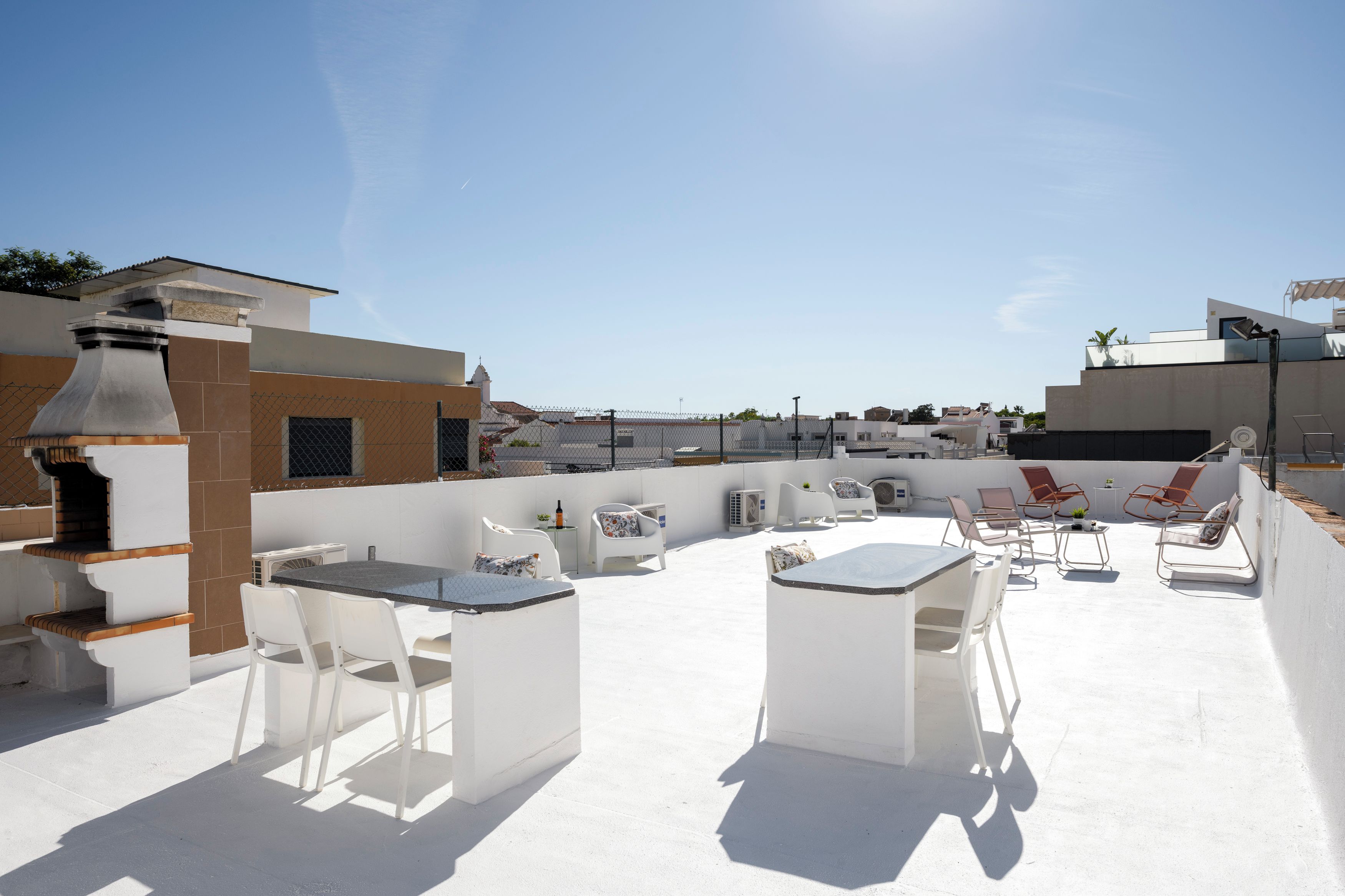 An outdoor patio with a barbecue, seating area, and a view of the cityscape.