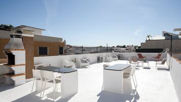 An outdoor patio with a barbecue, seating area, and a view of the cityscape.