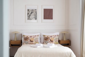 A hotel room with a bed, two nightstands, a radiator, and two framed pictures on the wall. - Casa Dona Irene Sunny Terrace | Room 1 | Early or Late Check-in (Faro)