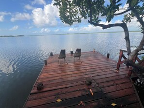 Eine Holzsteg mit zwei Stühlen und einem Tisch, mit Blick auf ruhiges Wasser.