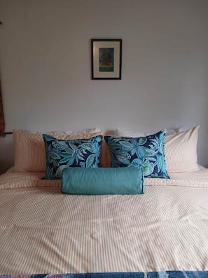 Ein Bett mit gestreifter Bettwäsche und zwei Zierkissen.