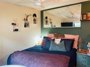 A bedroom with a bed, bedside tables, a mirror, and wall-mounted shelves with various items. - Puffing Billy Guesthouse: 
Escape the suburbs and enjoy the Dandenong Ranges! (Cockatoo)