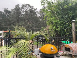 A patio area with a pizza oven, a grill, and a metal fence. - Puffing Billy Guesthouse: 
Escape the suburbs and enjoy the Dandenong Ranges! (Cockatoo)