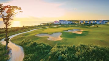 Un parcours de golf avec des bunkers, un sentier pédestre et des maisons en arrière-plan.