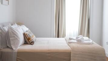 Une chambre d’hôtel avec un lit, des oreillers, une couverture et des serviettes.