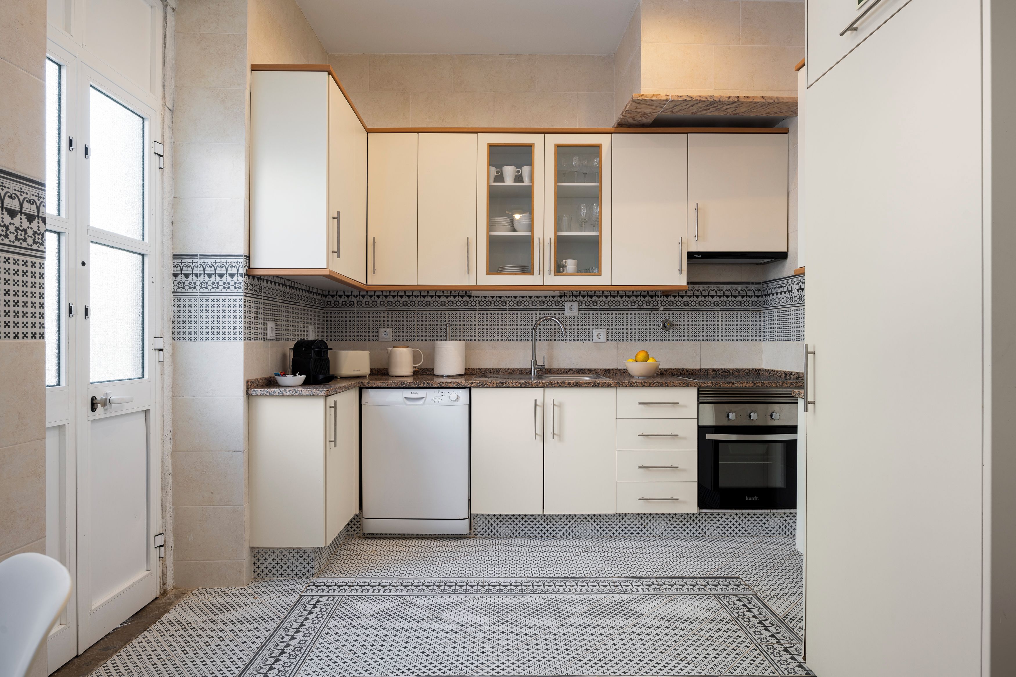 Bright full kitchen with patterned tile, dishwasher, and ample storage