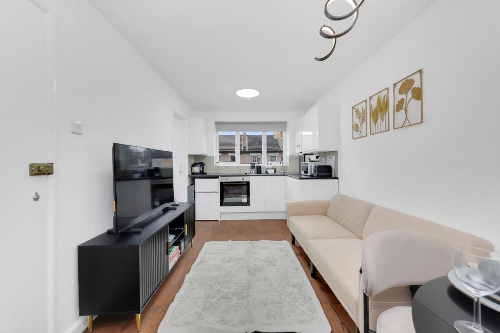 Un espacio habitable compacto con kitchenette, televisión de pantalla plana, sofá y zona de comedor.