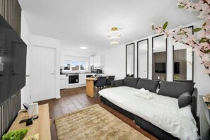 Un dormitorio moderno con una cama grande, un comedor y una cocina al fondo.