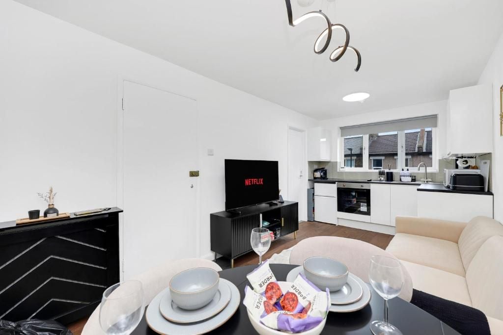 Una sala moderna con comedor, cocina y un televisor que muestra Netflix.