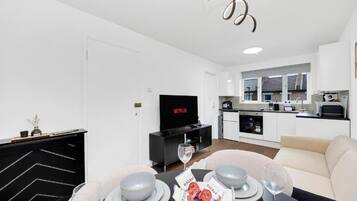 Una sala moderna con comedor, cocina y un televisor que muestra Netflix.