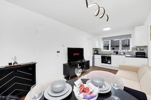 Una sala moderna con comedor, cocina y un televisor que muestra Netflix.