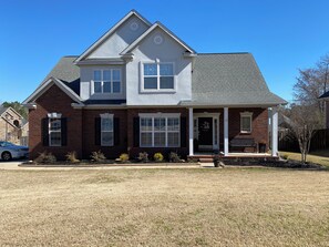 A two-story house with a front porch, a garage, and a well-maintained lawn. - Quaint 4-bedroom house with pool in charming Evans (Evans)