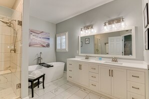 Ein modernes Badezimmer mit Badewanne, einem großzügigen Waschtisch mit Spiegel und einer Duschkabine.