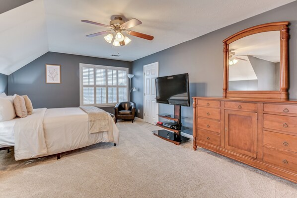 A bedroom with a bed, a dresser, a television, and a ceiling fan. - Quaint 4-bedroom house with pool in charming Evans (Evans)