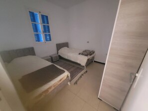 Un dormitorio con dos camas, una ventana con persianas y una puerta.