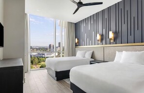 A hotel room with two beds, a ceiling fan, a large window with a city view, and wall-mounted lights. - 2 BR deluxe suite w/kitchen at Centennial Park. Walk to Mercedes-Benz stadium. (Atlanta)