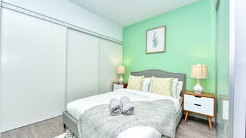 A modern bedroom with a bed, nightstands, and a wall-mounted lamp.