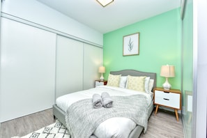 A modern bedroom with a bed, nightstands, and a wall-mounted lamp. - The Modern Suites - Downtown Toronto (Toronto)