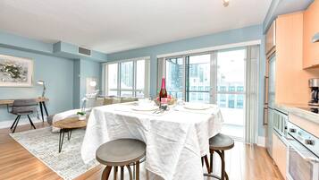 A modern kitchen with a dining area, large windows, and a view of the city.