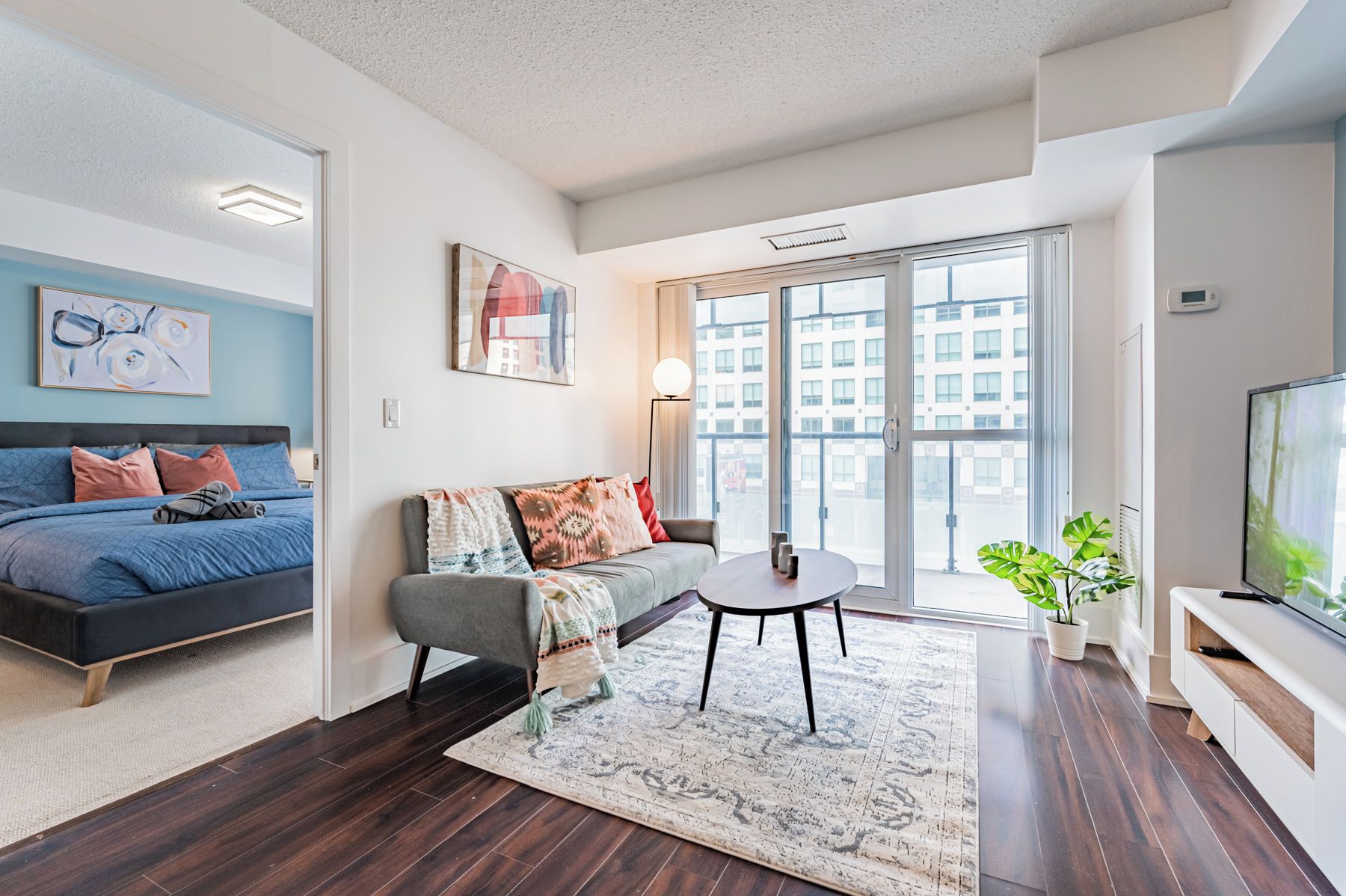 Una habitación de hotel moderna con cama, sofá, mesa de centro y televisión.
